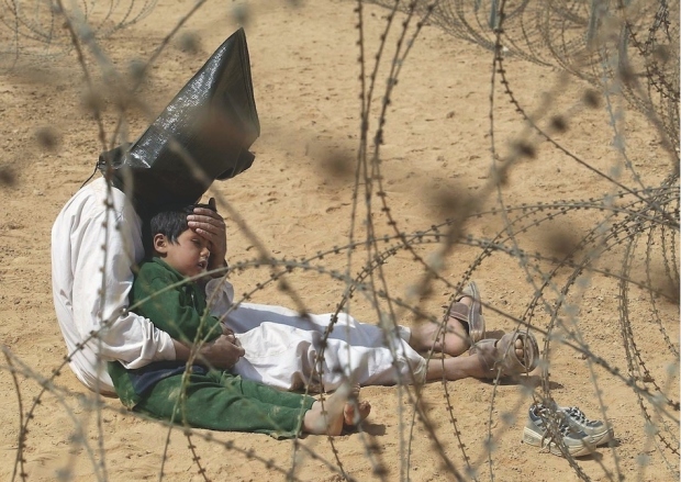 2003: Ιρακινός καθησυχάζει τον τετράχρονο γιο του, σε κέντρο αιχμαλώτων πολέμου. Το αγόρι τρομοκρατήθηκε, όταν, σύμφωνα με τις εντολές, περάστηκαν χειροπέδες και κουκούλα στον πατέρα του. Στην συνέχεια του αφαιρέθηκαν οι χειροπέδες απο τον κρατούμενο, προκειμένου να μπορέσει να ηρεμήσει το παιδί.