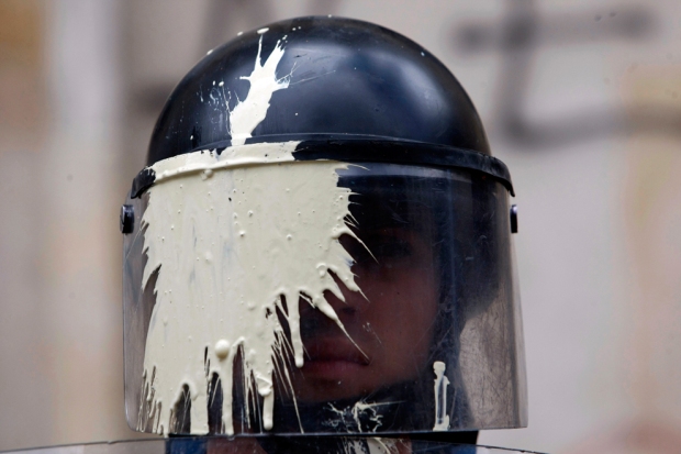 Αστυνομικός ΜΑΤ με τη μάσκα του βαμμένη από μπογιά που του ριξανε  μαθητές παρακολουθεί την πορεία από τους εκπαιδευτικούς και τους μαθητές που διαμαρτύρονται για θέματα που αφορούν τις εκπαιδευτικές πολιτικές της κυβέρνησης στην Μπογκοτά, Κολομβία